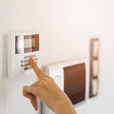 Young woman entering authorization code pin on home alarm keypad. Home security concept